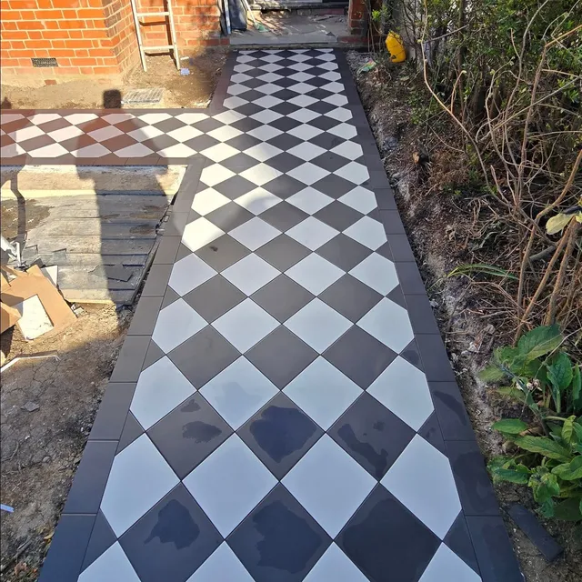 Outdoor path tiled in a diagonal black-and-white checkerboard pattern.