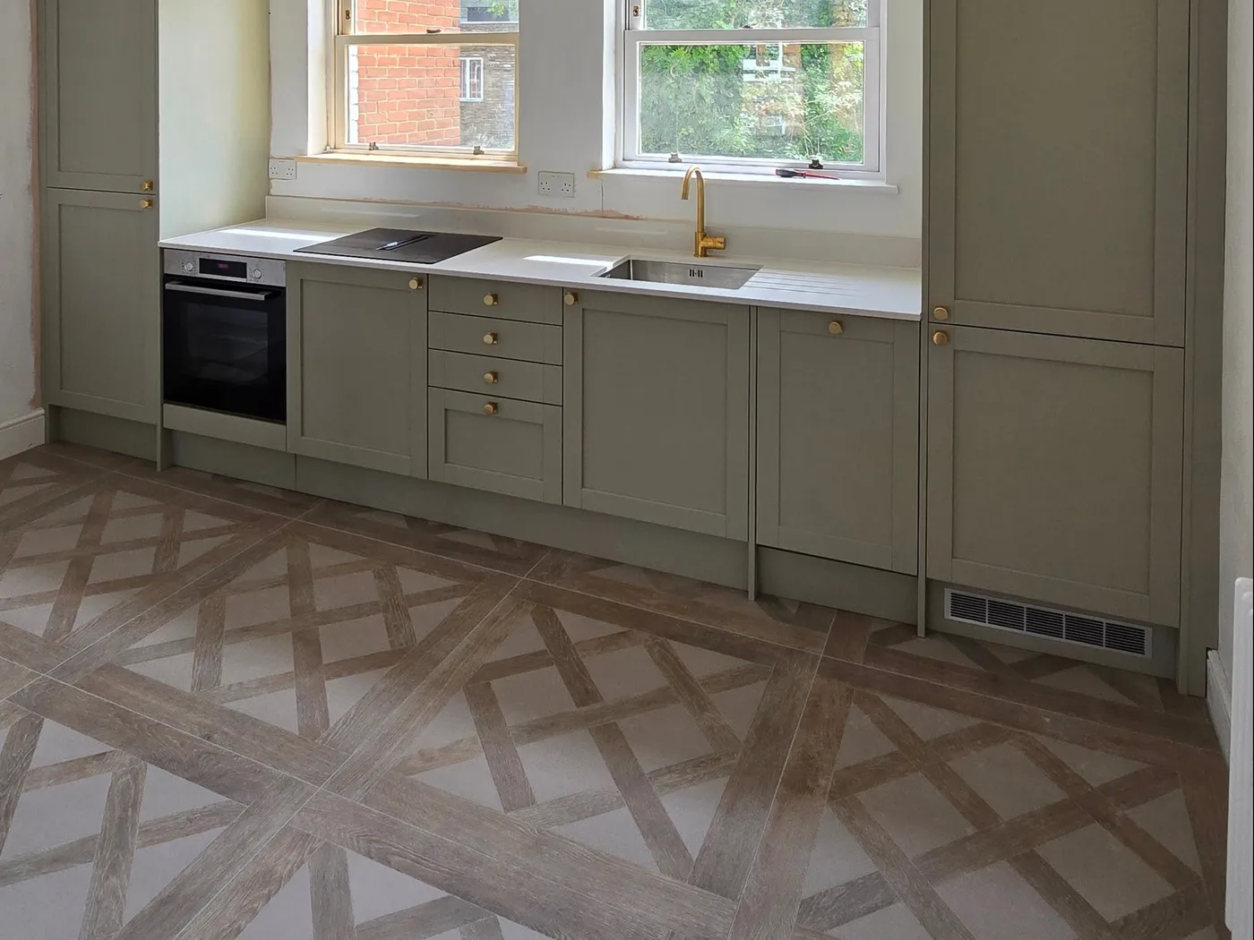 Completed kitchen with geometric patterned floor tiles and sage green cabinets.