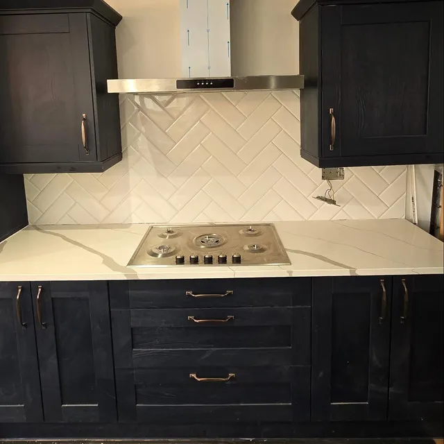 Kitchen splashback tiled in a herringbone layout behind fitted cabinets.