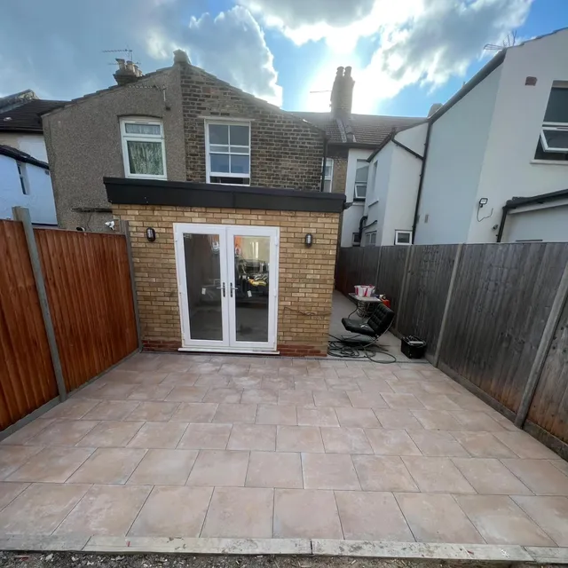 Exterior patio paved with large-format stone-effect tiles leading to glazed garden doors.