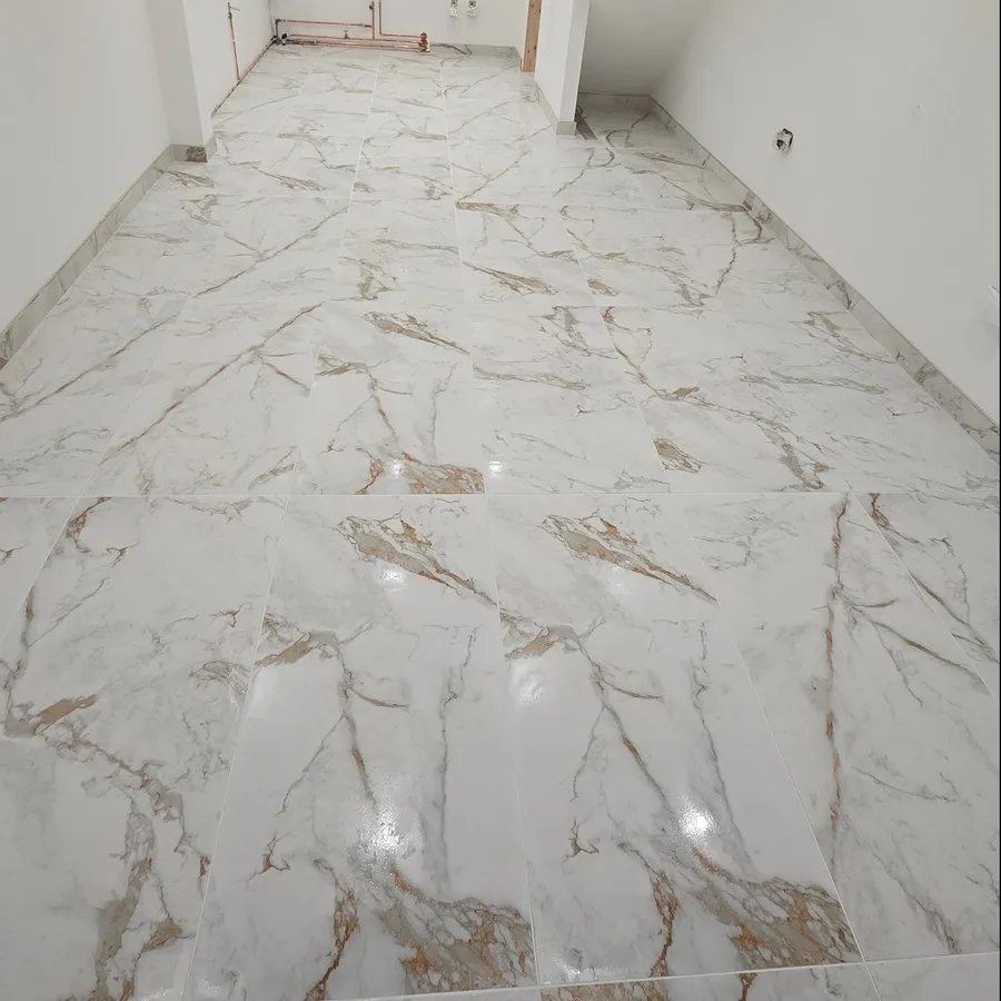 Long interior floor of large-format marble-effect tiles with matching tiled skirting.