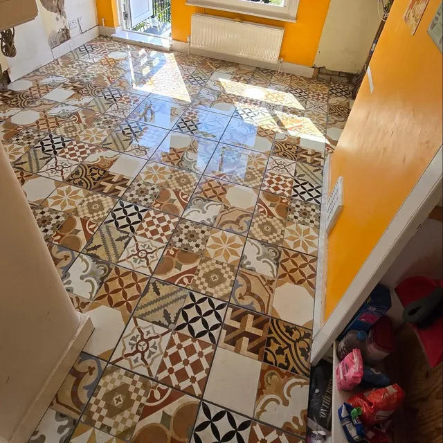 Kitchen floor of mixed patterned ceramic tiles in warm tones.