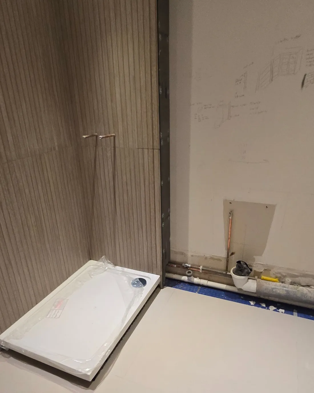 Partial tiling beside handwritten setting-out notes on an adjacent wall during preparation.